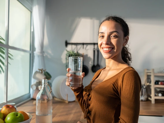 Person holding a a glass of clean water in a kitchen.